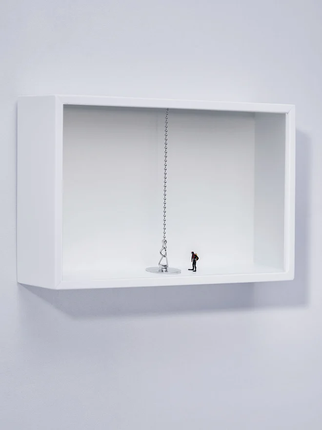 A tiny diver stands in front of a (relatively) huge plug in a white box (whole artbox)