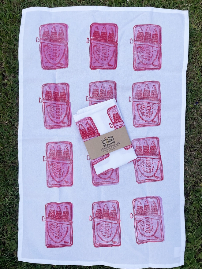 Pop of pink and red Sardine tea towel on garden background