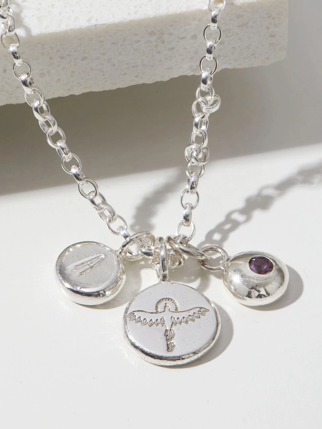 Close up image of a Sterling silver Phoenix Pebble Necklace with a letter and a birthstone charm
