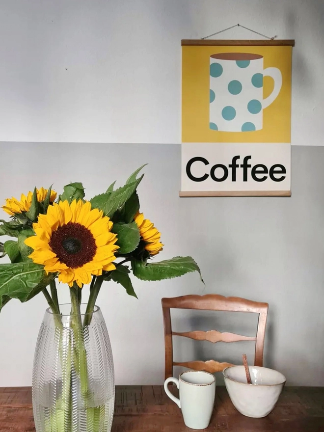 illustrated wall print featuring a mug of coffee beside a bunch of sunflowers