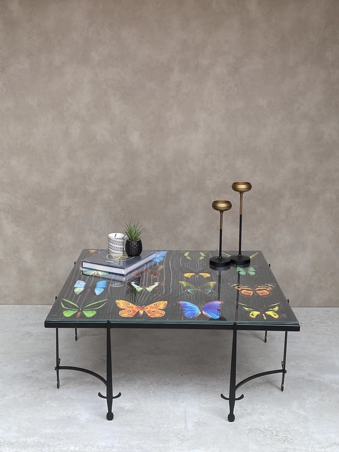 metal frame coffee table with artwork of colourful butterflies on top