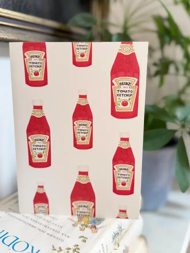 tomato ketchup bottles illustrated card. card placed on top of book pile on shelf.