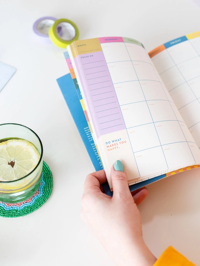 A close up view of colourful positive quotes sprinkled through out the daily planner. On an undated monthly spread it reads 'Do what makes you happy'.