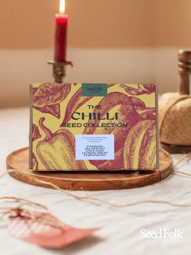 The Chilli Seed Collection Box. Beautiful box illustrated in yellow and red botanical print, photographed on a wooden tray. 
