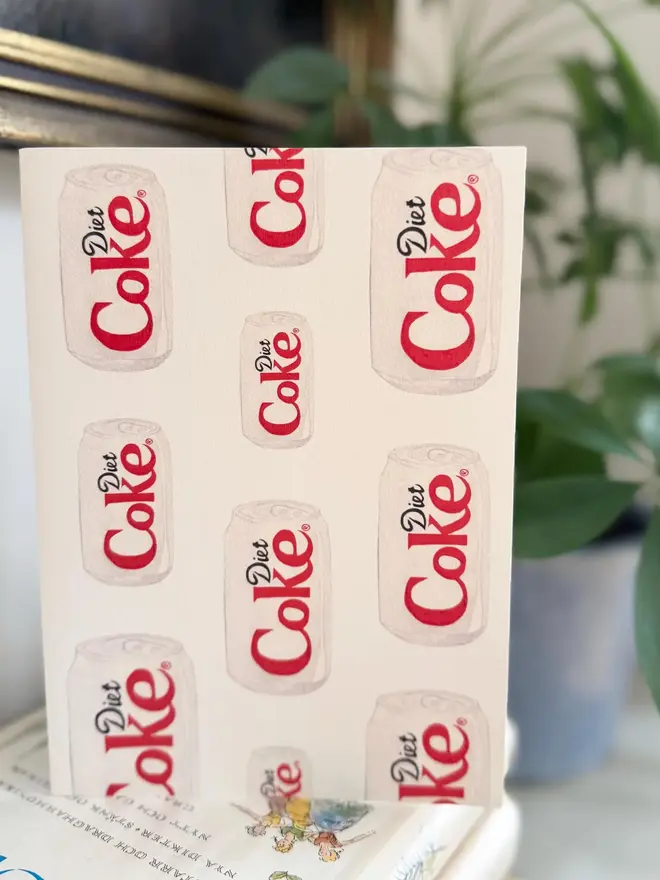 diet coke cans illustrated card. card photographed on top of book pile.