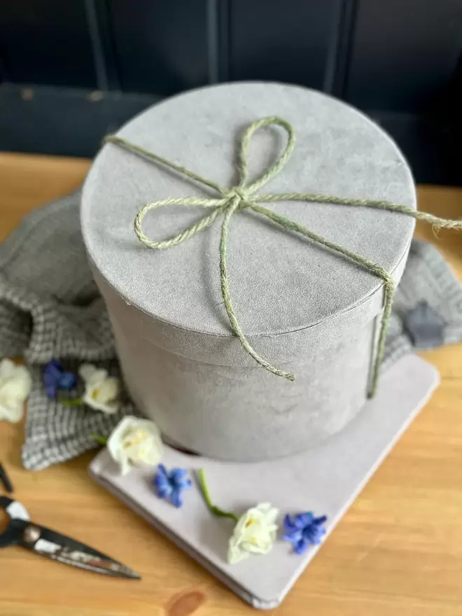 Grey velvet hat box filled with flowering hyacinths, quail feathers and quail eggs