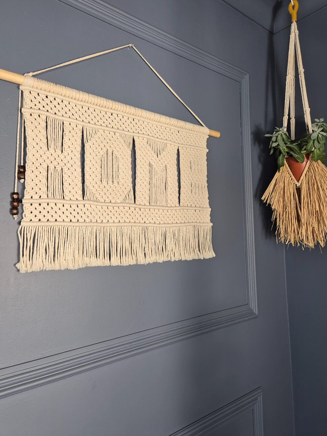 Macrame wall hanger featuring the word 'HOME' knotted beautifully in square knots to create a strong visual statement for entryways, living room, bedroom and any cozy empty spaces