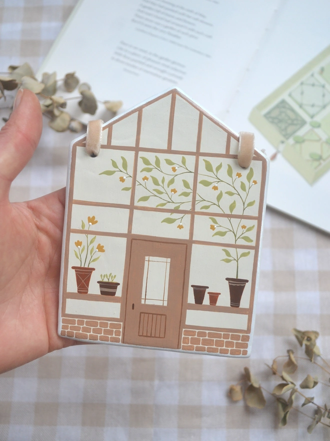 white ceramic hanging decoration with brown greenhouse illustration design