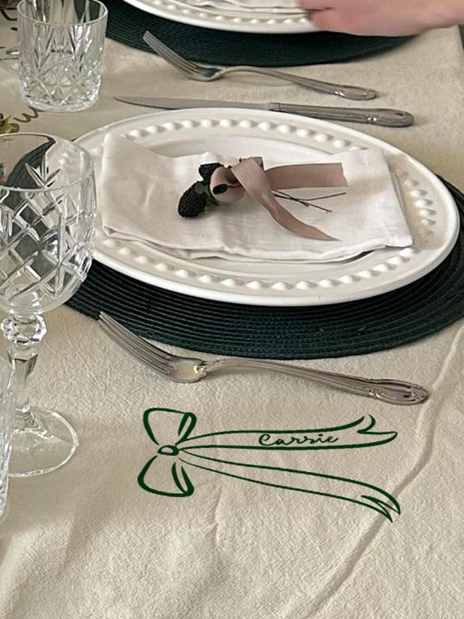 personlaised Bow tablecloth place name sticker green on a cream tablecloth