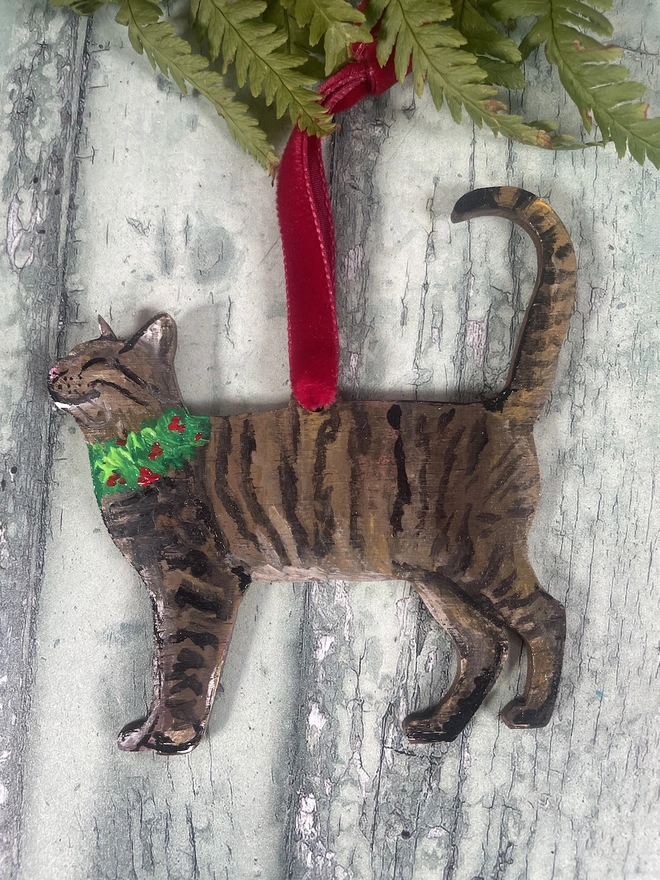 Tabby Cat Christmas Decoration with red velvet ribbon placed onto a book about cats 