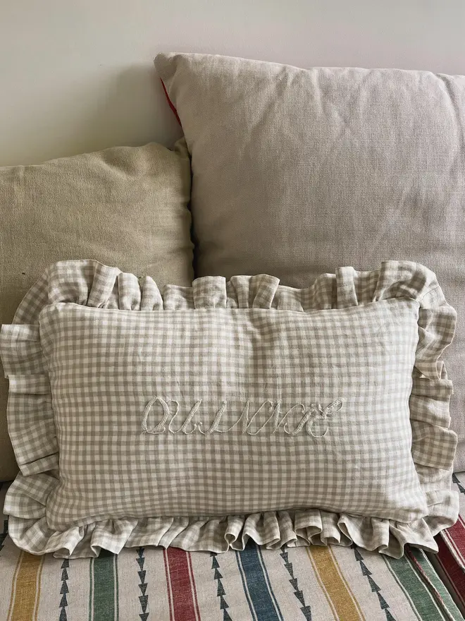 Personalised Handmade Embroidered Linen Cushion With Ruffle, oat gingham cushion on a sofa with a personalised message. 