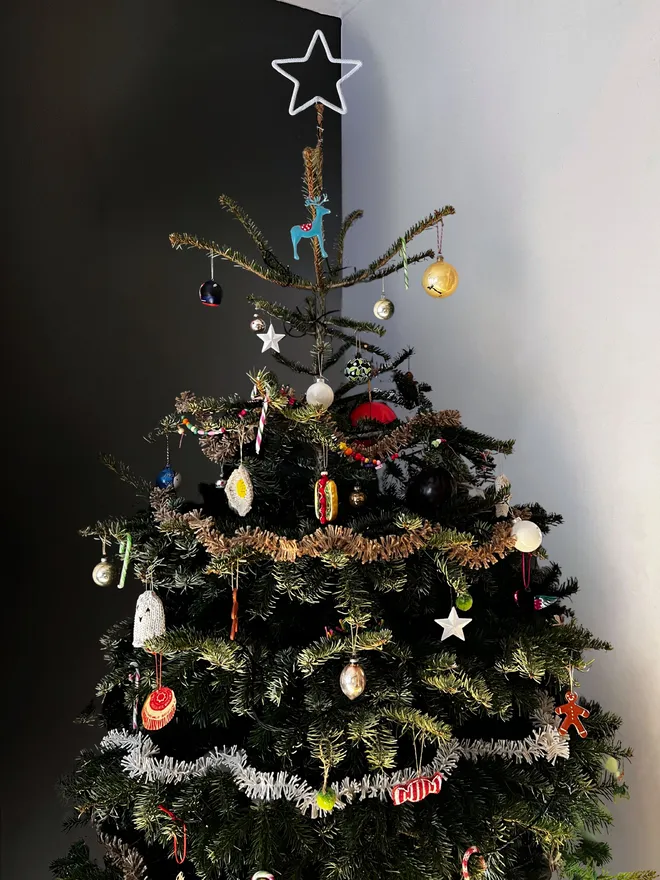 Real Christmas tree topped with a string wrapped wire star decorated with sustainable heirloom decorations, cotton and jute Strinsel tinsel