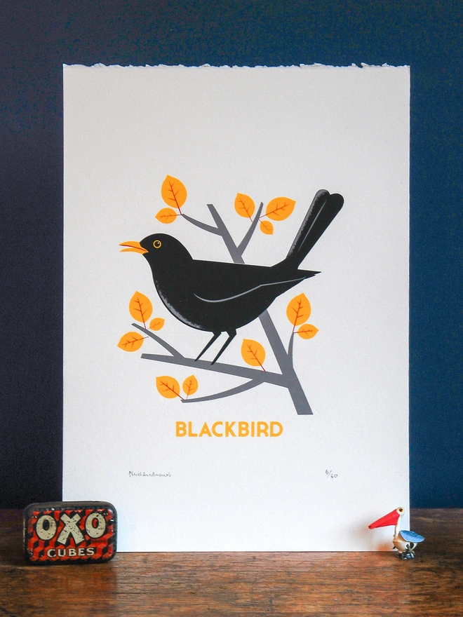 A screenprint of a Blackbird on white paper against a navy blue background.