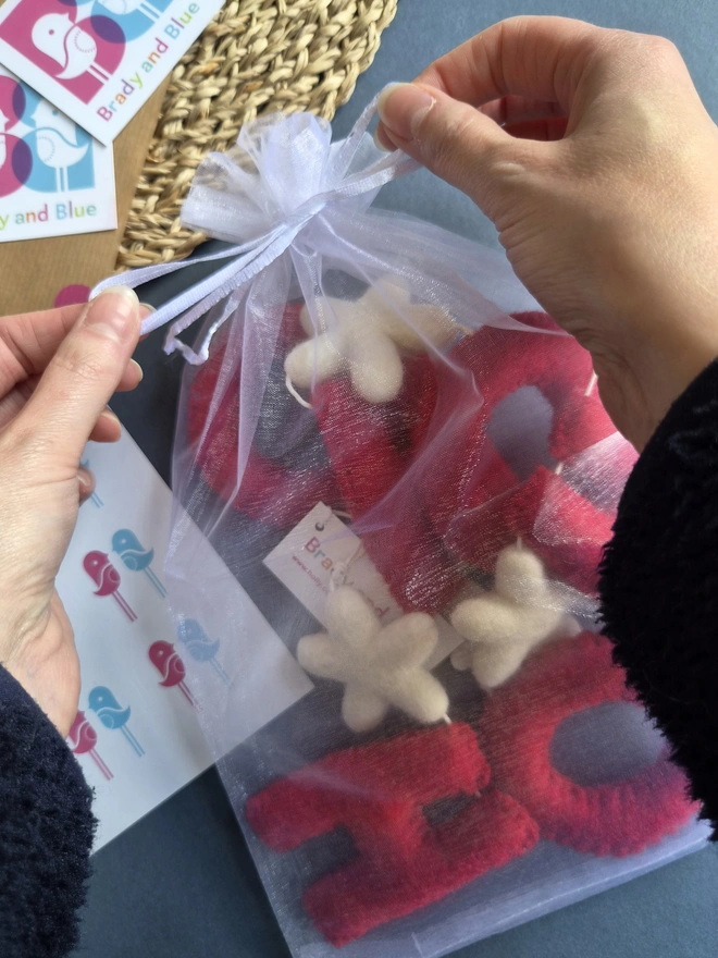 A red Christmas garland in an organza drawstring gift bag.
