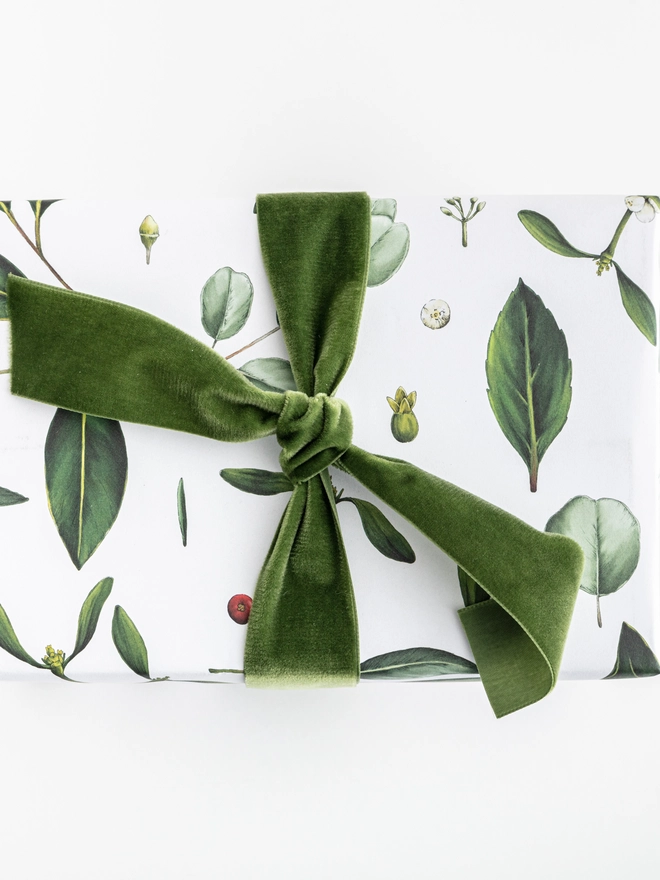 White base Christmas wrapping paper with a green foliage elements pattern