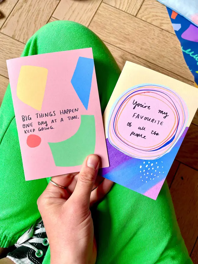 Nicola holds two colourful, meaningful cards