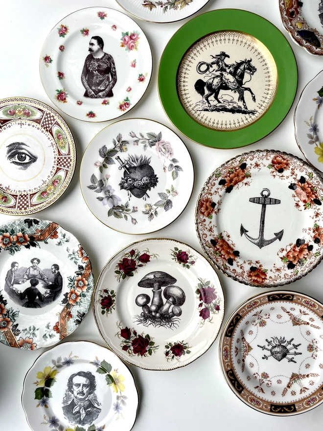 an eclectic collection of vintage plates hung together on a white wall, each plate is different with patterned or gold borders and vintage images in their centres