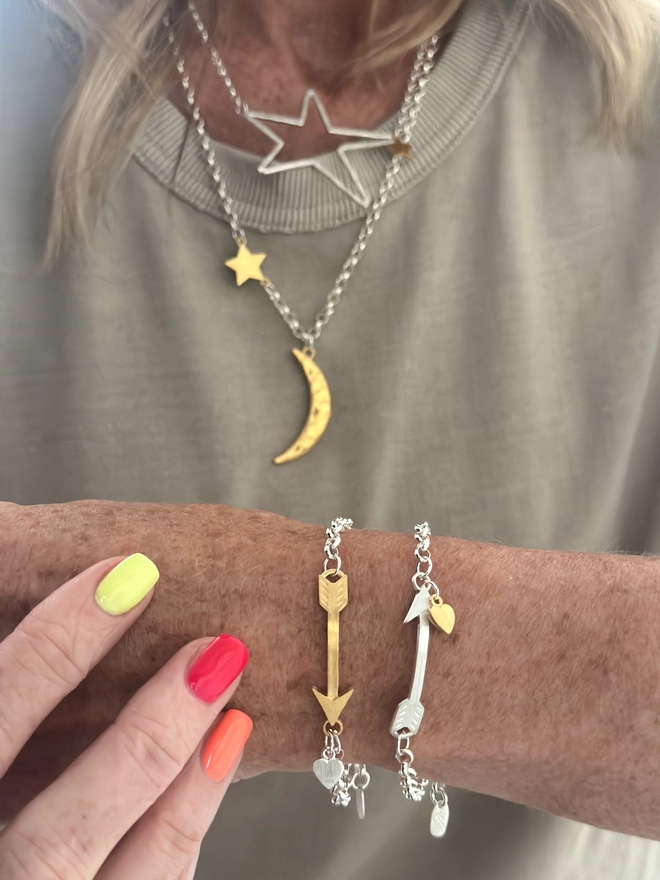 model wears sterling silver bracelet with gold arrow charm and small personalised silver heart charm