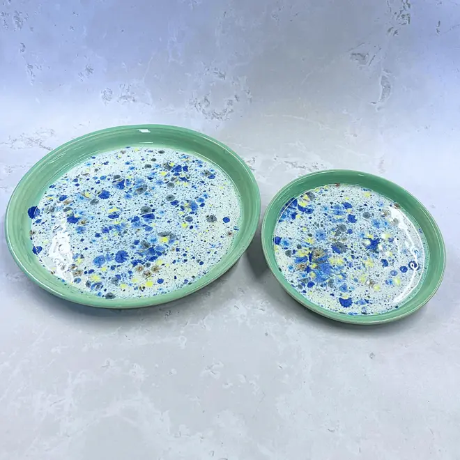 Shoreline Dinner Plate, a colourful plate placed on a stone surface. It is accompanied by a smaller colourful plate. 