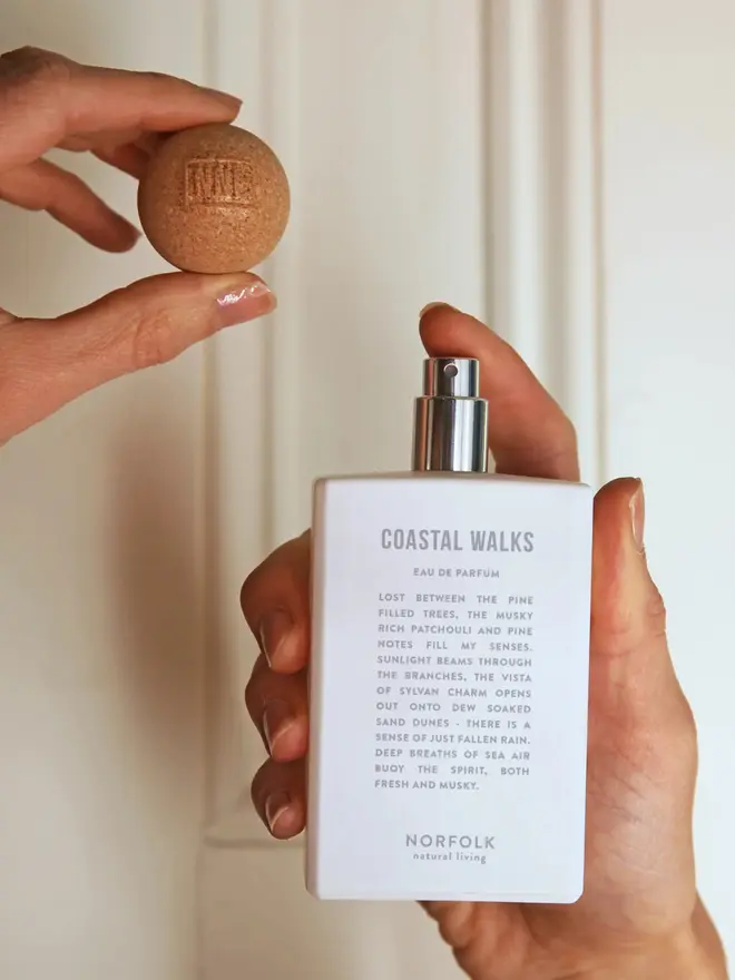 Coastal Walks Eau de Parfum bottle with cork lid in 100ml size, held up by two hands against a neutral background