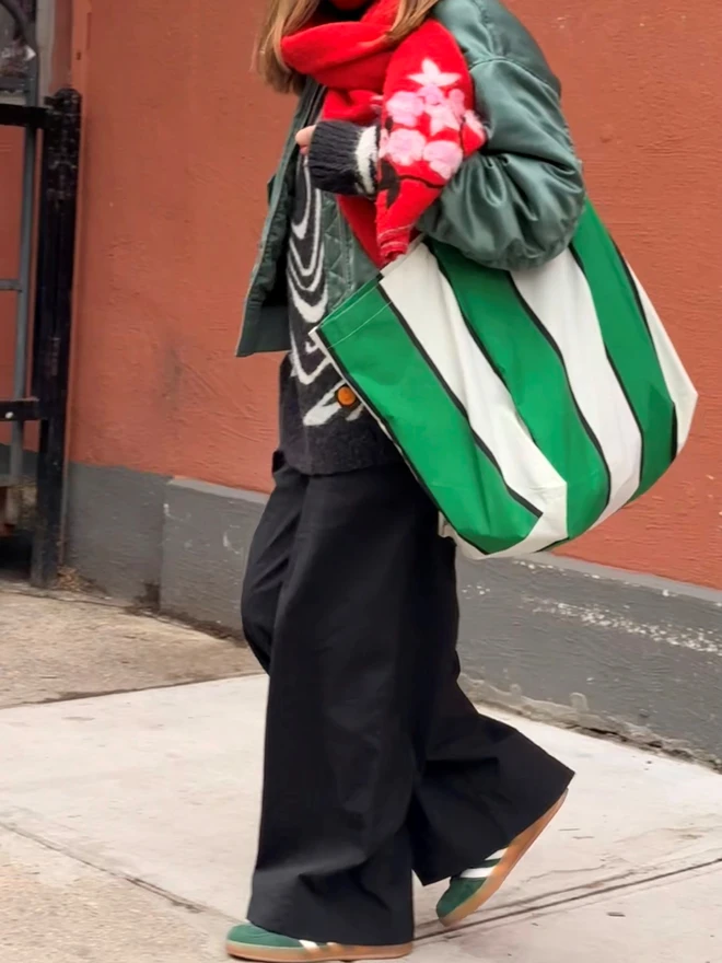 green stripe bag on arm of woman with red scarf