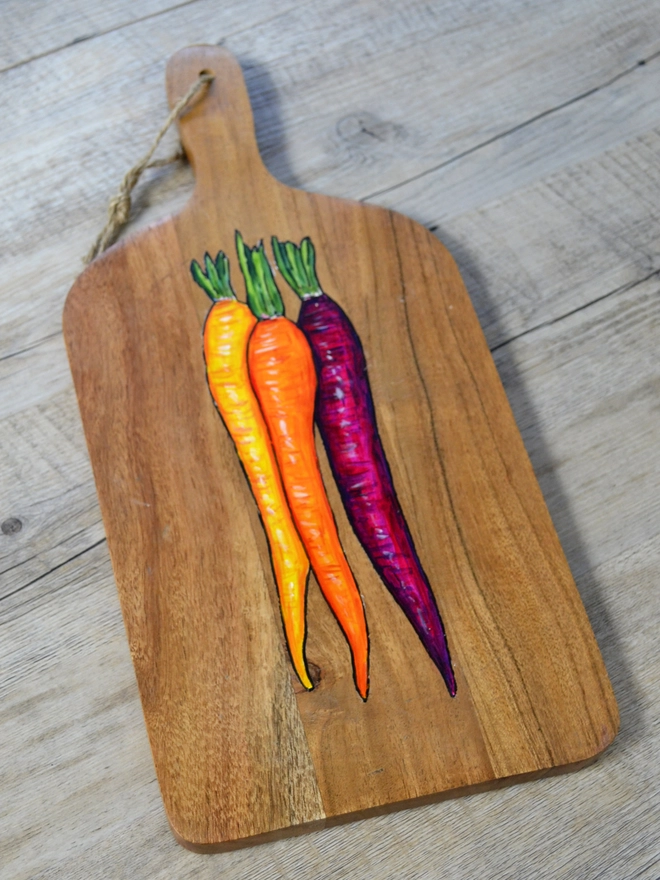 Wooden serving board with a handpainted carrots design