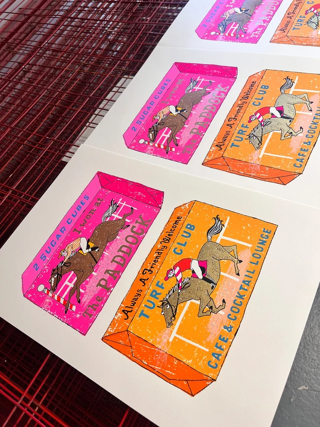 Two Horse Race Horse Sugar Cubes Screenprint, a pair of colourful sugar cube designs on a white screenprint. They are sitting on a studio rack. 
