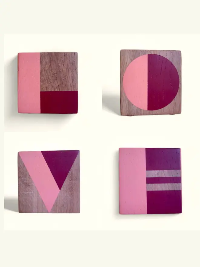 Four wood cubes painted with the letters L O V E in red and pink on white background