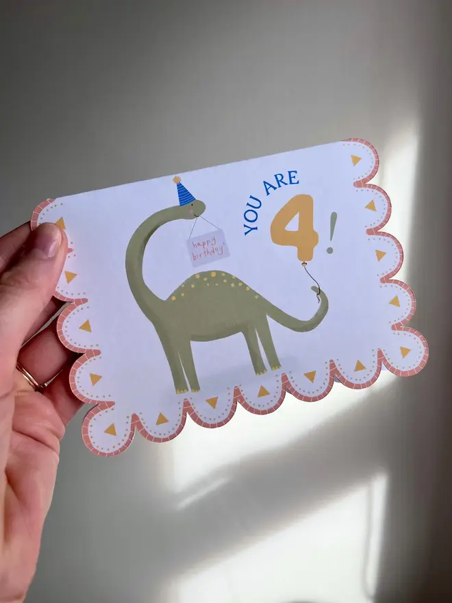 you are 4 dinosaur birthday card. scallop edged card with illustrated green dinosaur.