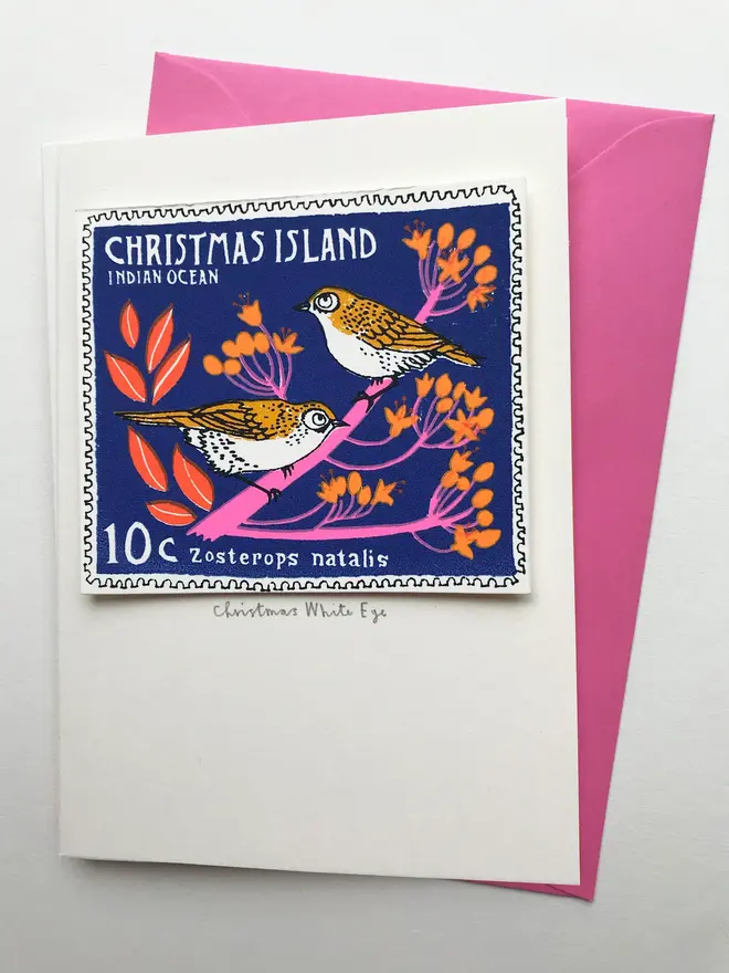 Bird Stamp Card Christmas Island White Eye Stamp, a Christmas card with a pair of birds stamp on a white surface with a pink envelope in the background. 