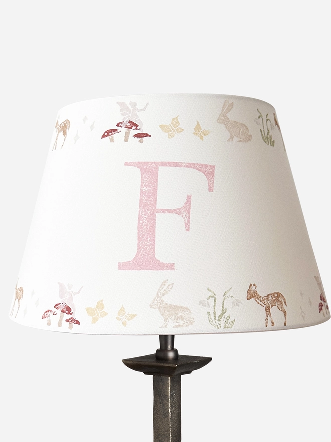 Studio Zef personalised woodland animals lampshade, a pink and cream empire lampshade featuring rabbits, deer, butterflies , fairies and mushrooms, designed as a pretty lampshade for kids bedroom décor.
