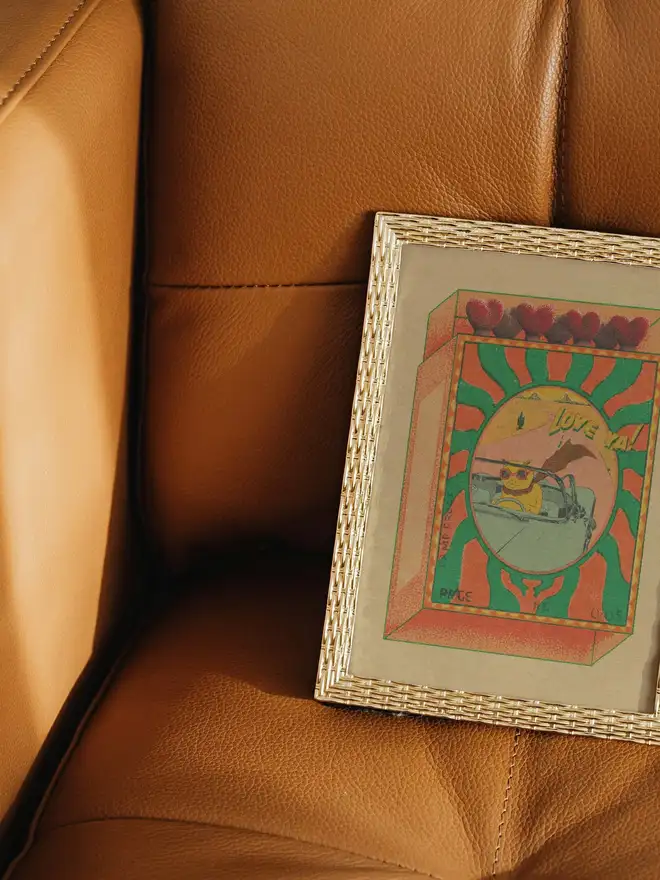 A playful burst of retro joy, Love Ya! captures a cool cat cruising through the desert in rose-tinted shades. Framed like a whimsical matchbox, the scene glows with sun-soaked oranges and greens, hand-textured grain, and heart-shaped match heads lining the top. Equal parts nostalgic and cheeky, this print blends vintage travel posters with pop surrealism—perfect for adding warmth and character to any space.  The laid-back feline, sunglasses on and paws at the wheel, radiates carefree confidence and a wink of humor. It’s a love letter to the open road, sweet moments, and saying “love ya” without taking things too seriously.  Details  High-quality art print with rich, textured color  Retro color palette with desert and sunset tones  Perfect for living rooms, studios, offices, or as a unique gift  Ships carefully packaged to protect the artwork