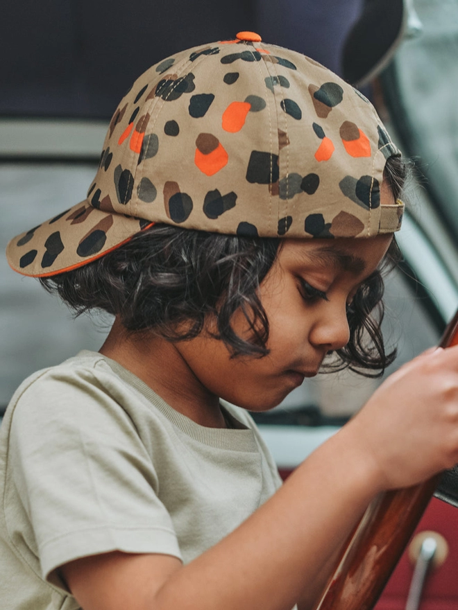 Boy wearing sun baseball cap in leopard neutral print