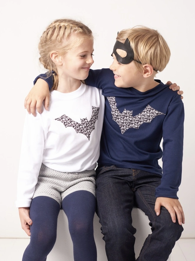 a 5 year old boy wearing a navy cotton t-shirt with a monochrome Liberty fabric bat sewn on the front.