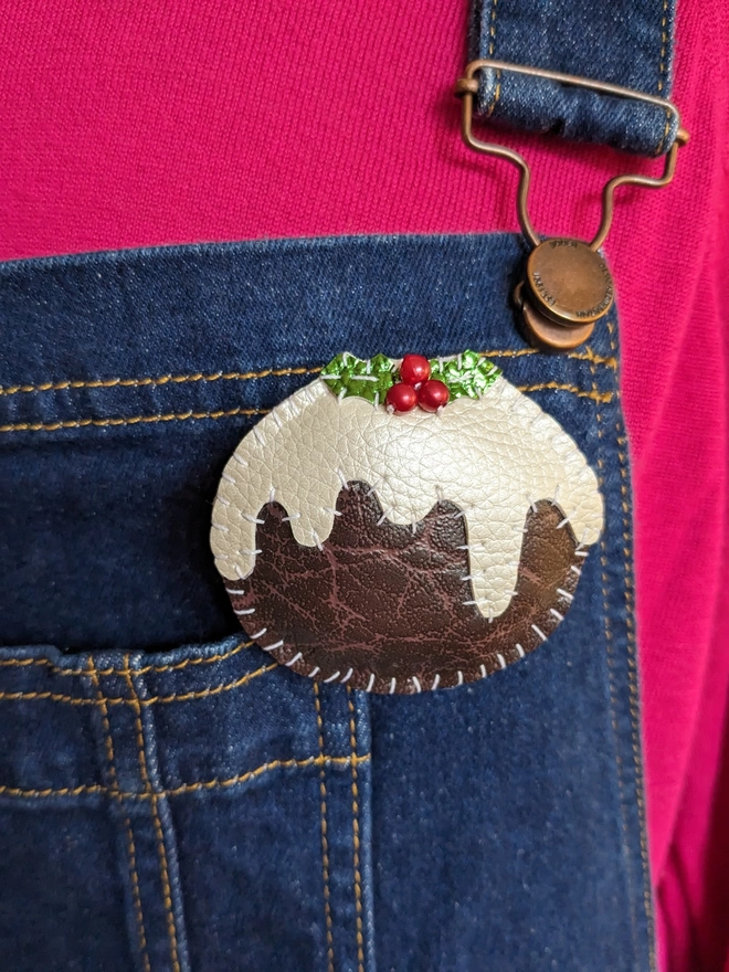 Faux leather christmas pudding brooch pinned onto adenim dungarees