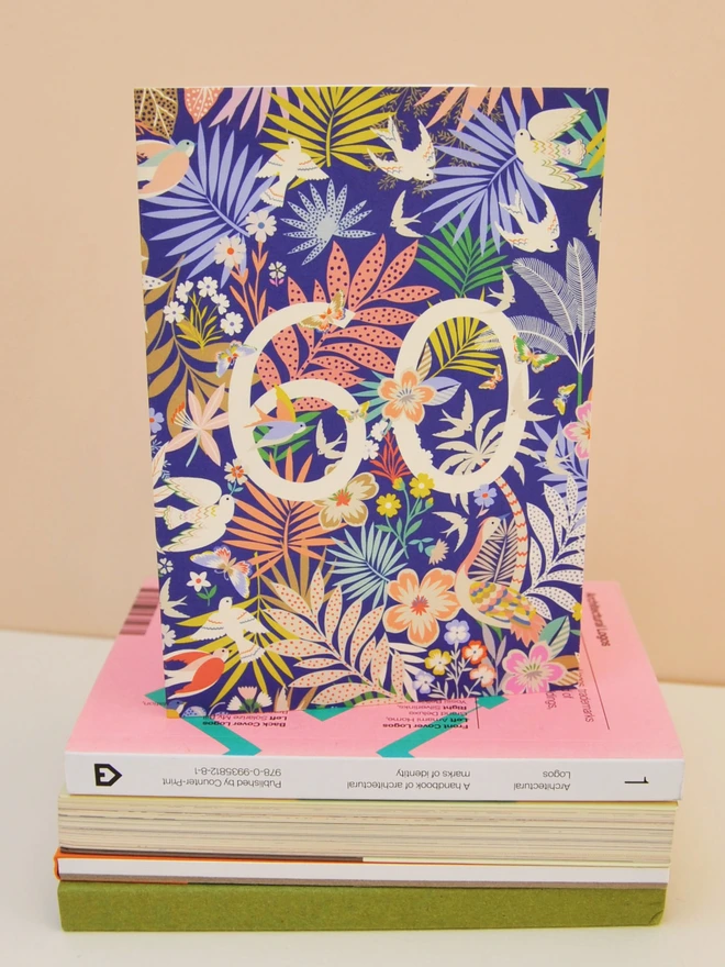 purple birthday card with floral and plant designs, with off white "60" 