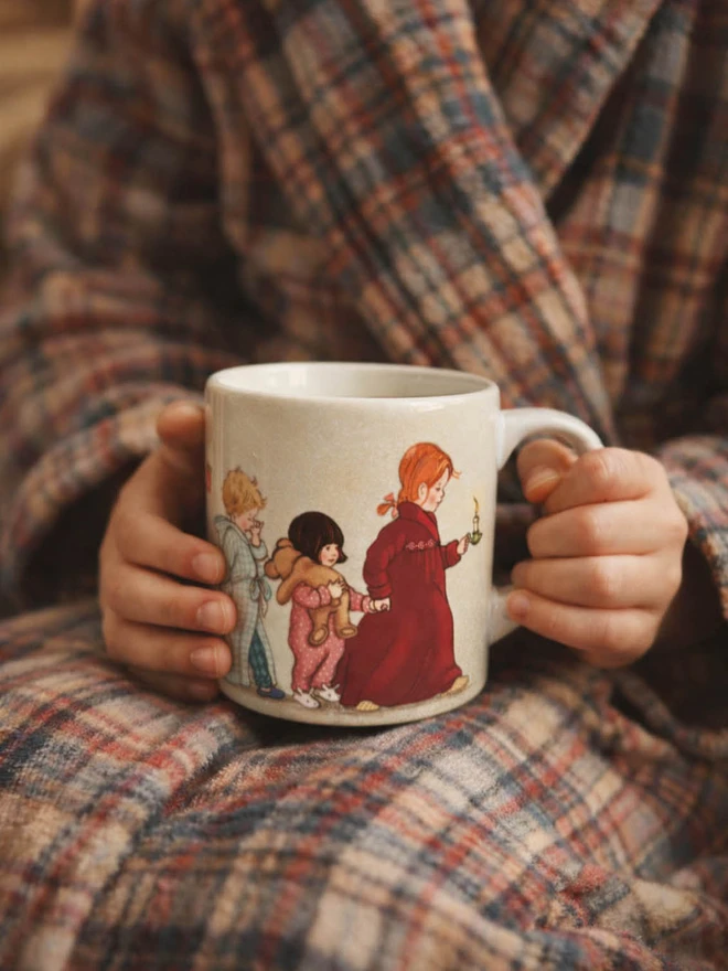 a cosy photo of a girl holding a sweet cosy ceramic mug illustrated witha traditional story book style illustration of children heading to bed