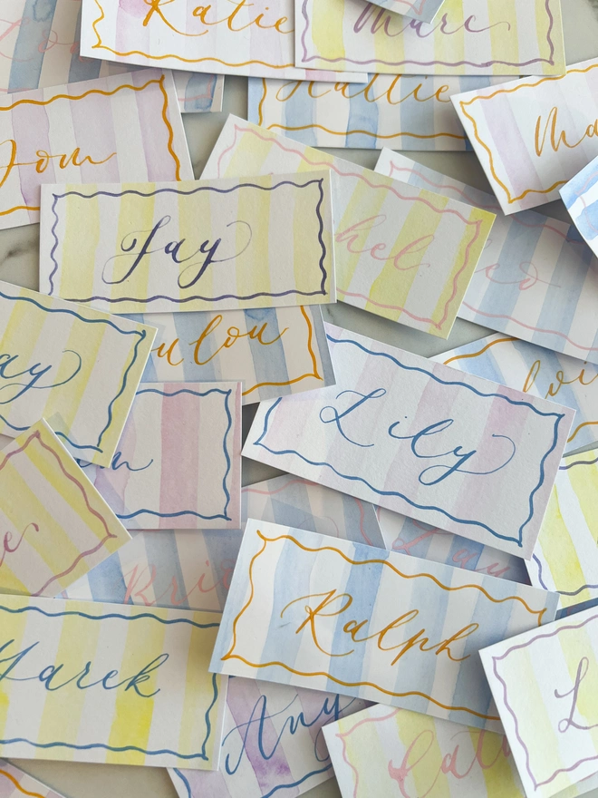 Personalised calligraphy event place cards, striped coloured place cards spread together