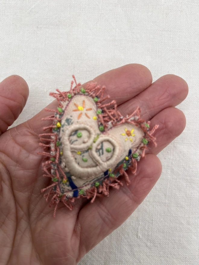 pink fringed brooch on hand