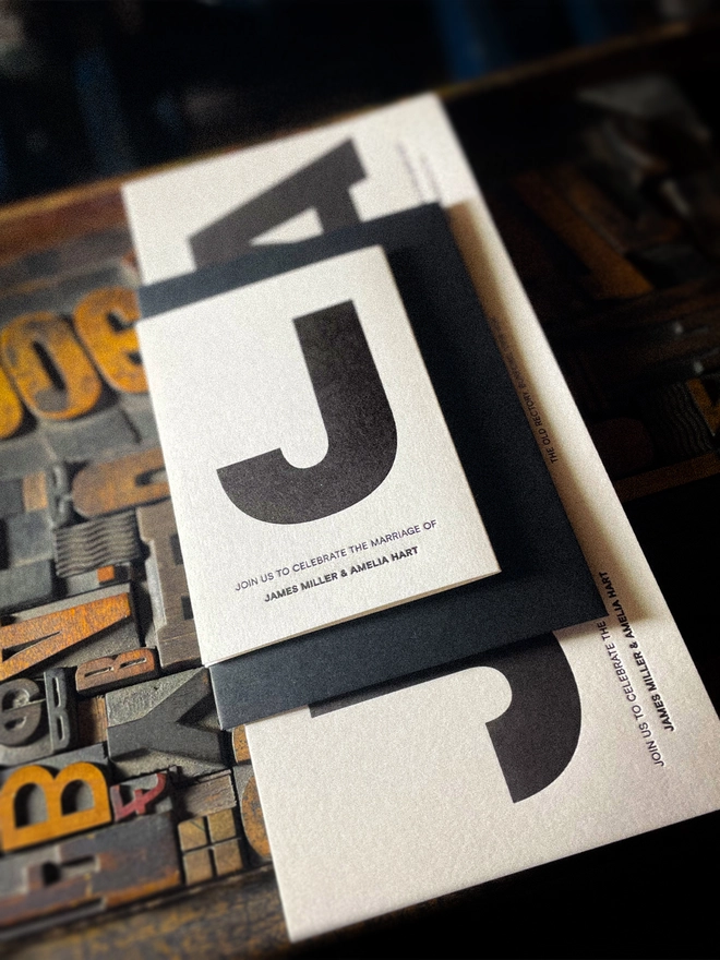 Close-up of Amour Mono personalised Save the Date with bold black typography, matching black envelope and tactile letterpress impression on luxury white card.