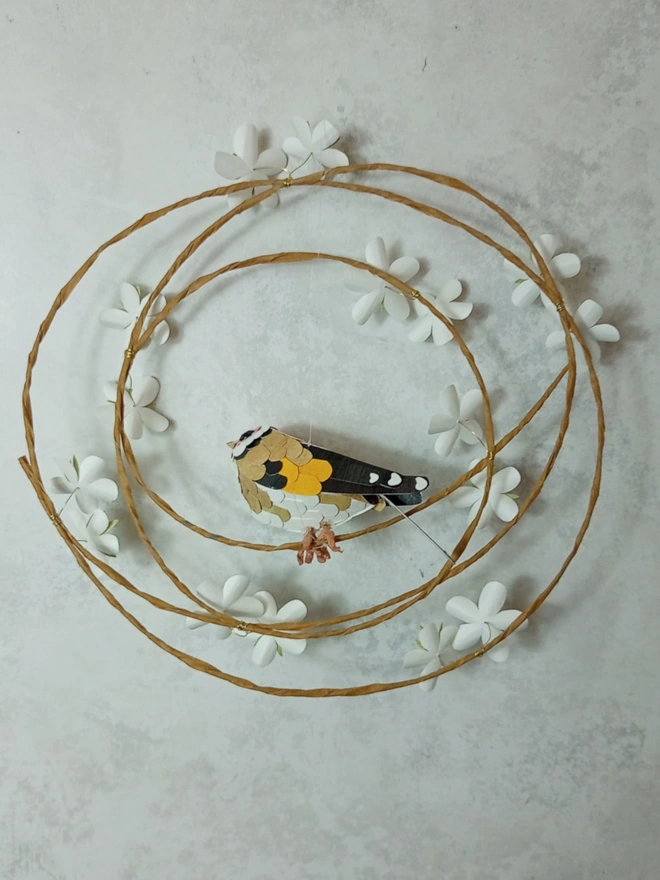 back view of a goldfinch sculpture on a blossom wreath