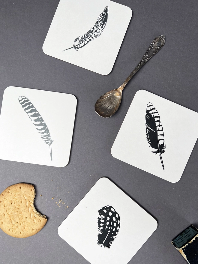 All four feather coasters together with a spoon and biscuit.