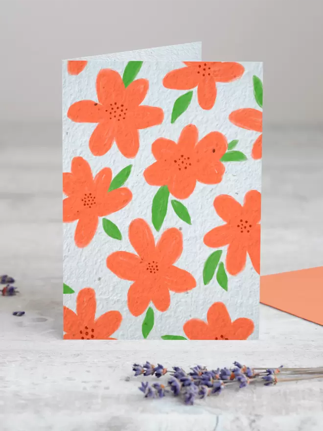 Seed Card with orange floral illustrations all over with a sprig of Lavender placed in the foreground of the image