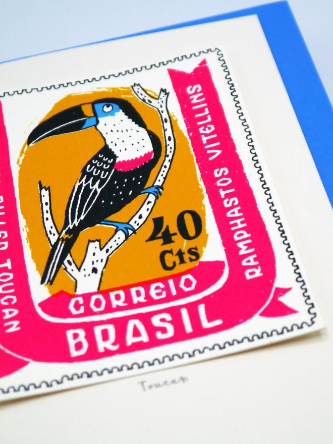 Bird Stamp Card Brazil Toucan, a white card with a toucan stamp against a plain background with a blue envelope. 