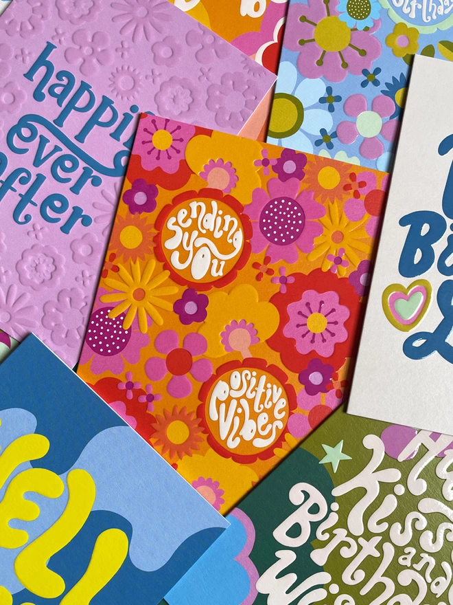 A pile of colourful cards from the Raspberry Blossom ‘Big Love’ greeting card collection. The cards are filled with vibrant floral and psychedelic patterns all with a spot UV and embossed finish