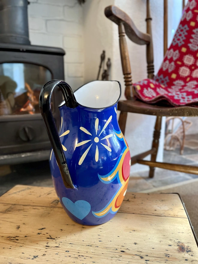 Vintage blue enamel jug hand painted with a fairground inspired design in pink, orange, yellow and red.