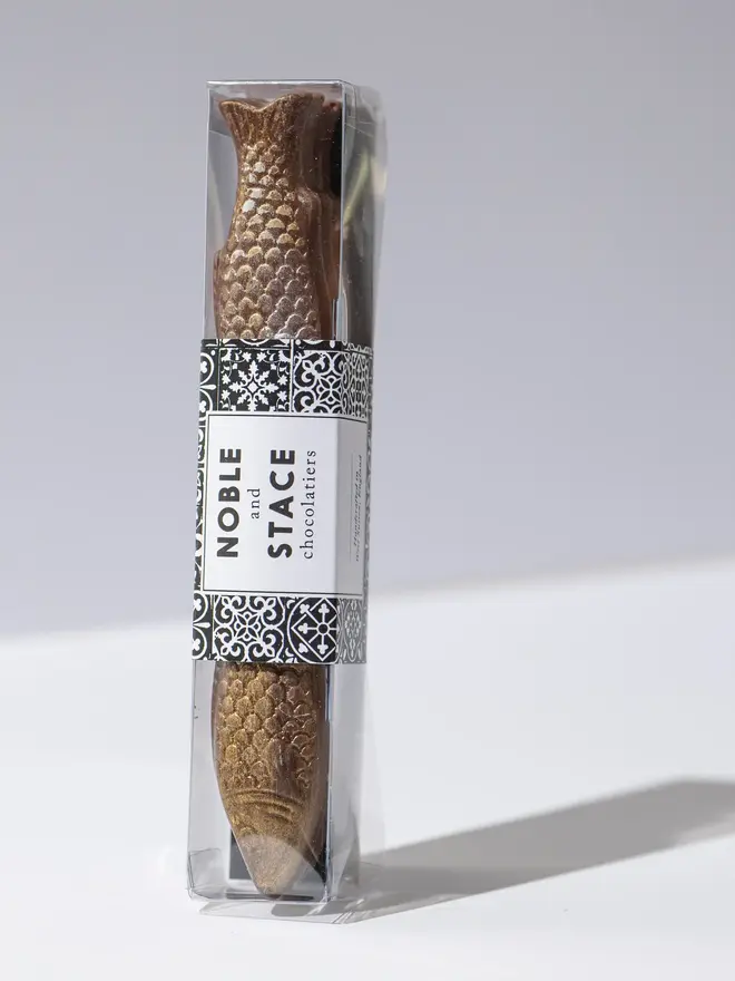 Chocolate fish wrapped and standing on a white table. 