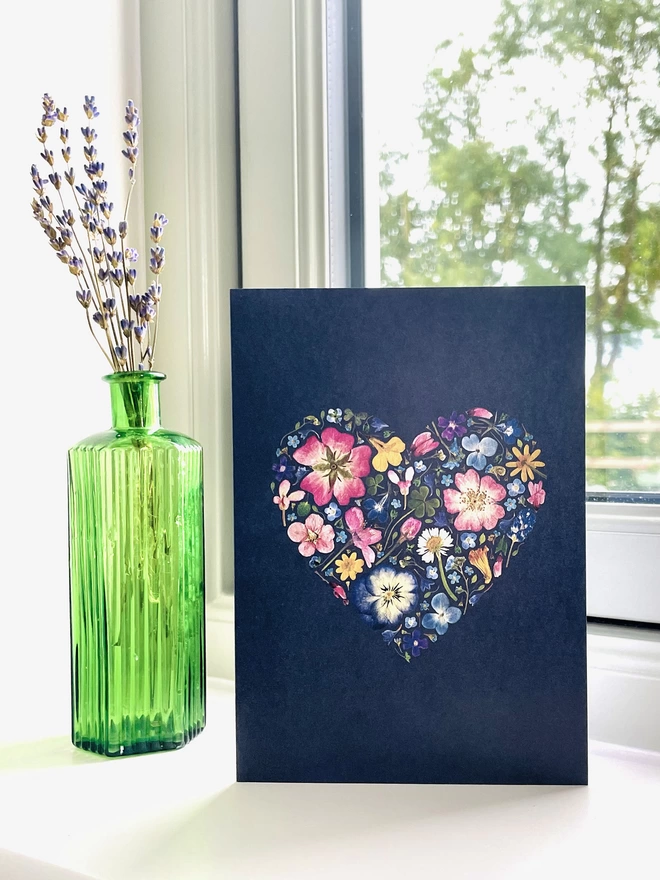 Dark Blue Greetings Card with Digitally Printed Pressed Flower Heart Design Standing on Windowsill - Green Glass Bottle with Dried Lavender - Garden View with Tree, Wooden Fence