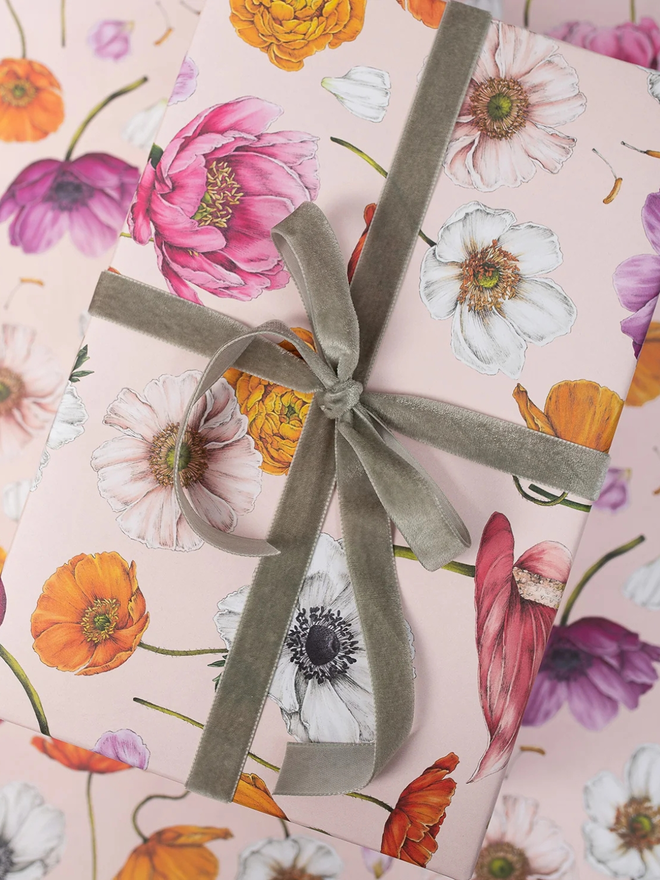 floral brights floral gift wrap sheet. a box wrapped in pale pink illustrated floral gift wrap with a green ribbon.