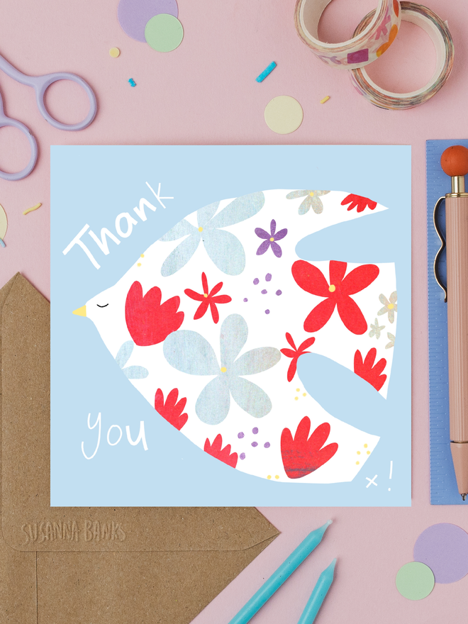 floral dove illustrated thank you card. card photographed on table with assorted crafting items.
